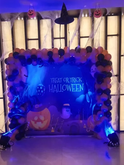 Spooky fun for a Halloween-themed party. This setup features a "Treat or Trick" backdrop, a balloon frame in classic orange and black, and spiderweb details.
