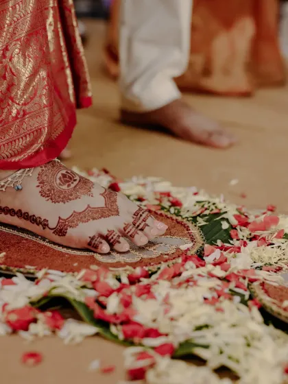 A candid shot of the bride's feet during a wedding ritual, showing the lovely dark stain of her foot mehndi.
