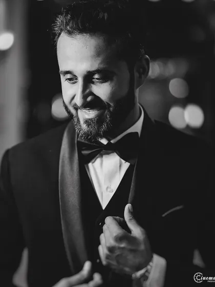 A candid black and white portrait of the groom, looking dapper in his tuxedo. This style adds a touch of classic Hollywood charm.