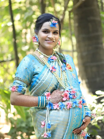 A beautiful maternity portrait. The client gently holds her baby bump, her face glowing with soft makeup that enhances her natural features. The look is completed with a traditional nose ring and floral accessories.