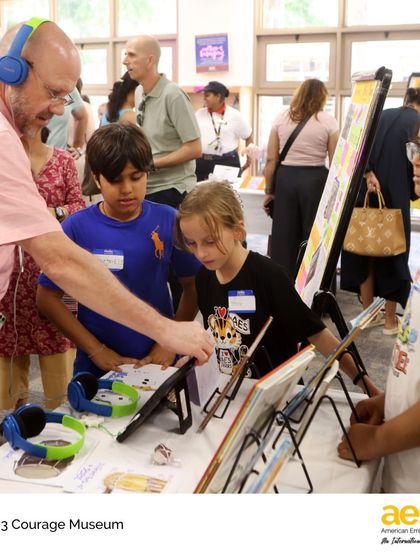 Interactive learning at the Courage Museum. A teacher uses headphones to listen to a student's recorded interview, part of their multimedia exhibit on what it means to be courageous.