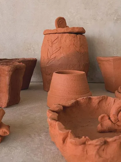 A variety of terracotta pieces made by our students, from a snail bowl to a lidded jar with leaf engravings.