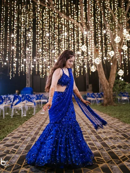 A beautiful full-length shot of the bride in her shimmering blue lehenga, twirling under a canopy of fairy lights.