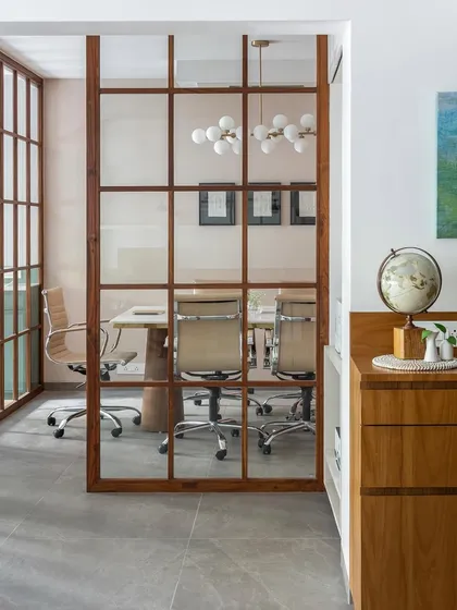 A view into the conference room through the teak wood and glass grid partition. This design element promotes a sense of openness and transparency while still providing acoustic privacy.
