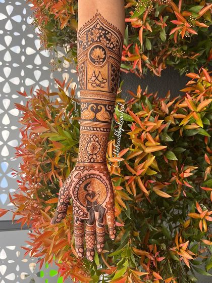 A single arm view of the engagement mehendi, highlighting the portrait of the bride. The arm design includes swans and a lotus, symbols of beauty and purity.