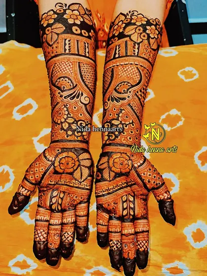 This full coverage Indian bridal design uses bold lines and dark filled areas to create a striking contrast. The floral patterns on the palm and wrist stand out beautifully.