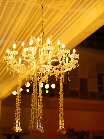 A detail shot of a chandelier adorned with strings of fresh mogra flowers, a beautiful fusion of classic elegance and traditional Indian decor.