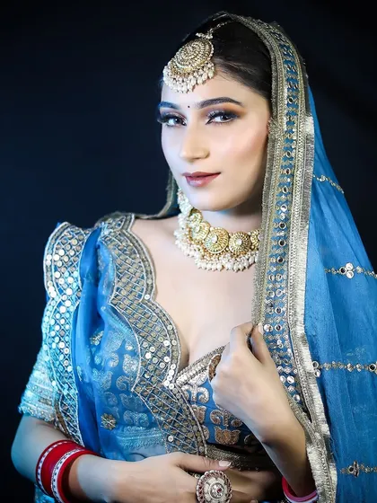 A classic bridal portrait against a dark background, making the blue and gold of her outfit pop. The lighting techniques used here are part of what you'll learn in our portfolio development sessions.