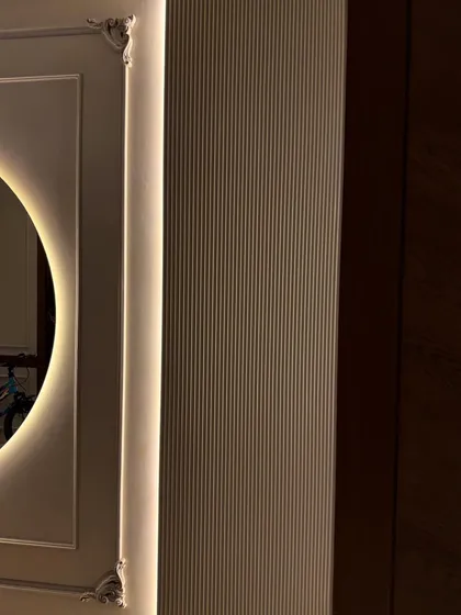 A detail shot of the corner of the backlit mirror, showing the intricate molding and the soft glow of the hidden LED strips.