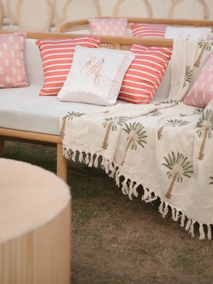 A personalized cushion with the couple's initials, paired with a custom block-printed throw. These bespoke details at the 'Mantram' wedding made the lounge area feel personal and welcoming.