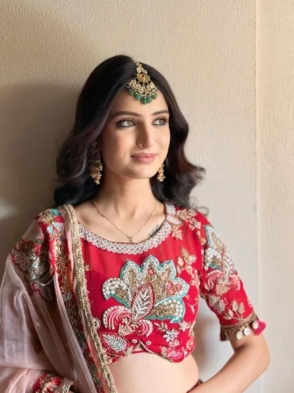 A close-up of her makeup, featuring a soft smoky eye and a nude lip, letting the vibrant red outfit shine.