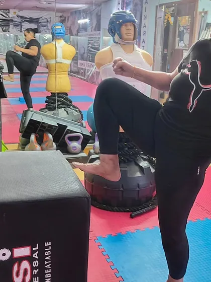 A student practices her knee strikes on a training box. This exercise builds power in close-range combat techniques, a vital part of self-defense.