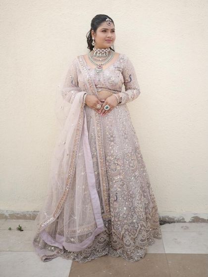 A full length view of the ivory lehenga, paired with a heavy diamond and pearl necklace set. It’s a sophisticated look for any formal occasion.