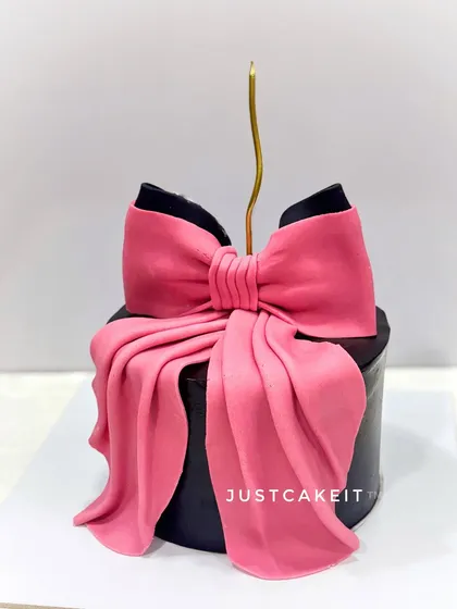 A chic and bold cake featuring a large, dramatic pink bow on a black cake. This minimalist design makes a big statement.