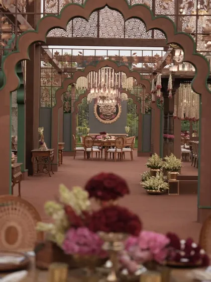 A long shot of the dining hall, showing the repetition of grand arches and chandeliers that create a sense of infinite luxury and grandeur.