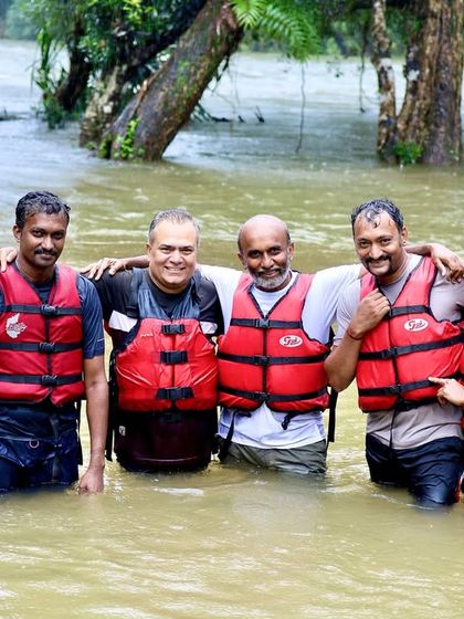 A group of friends and fellow adventurers pose for a photo in the water, celebrating the completion of their rafting expedition in Coorg.