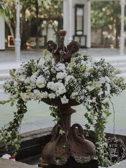 A fountain at the venue becomes a stunning decor piece, filled with an overflowing arrangement of white flowers and cascading ivy.