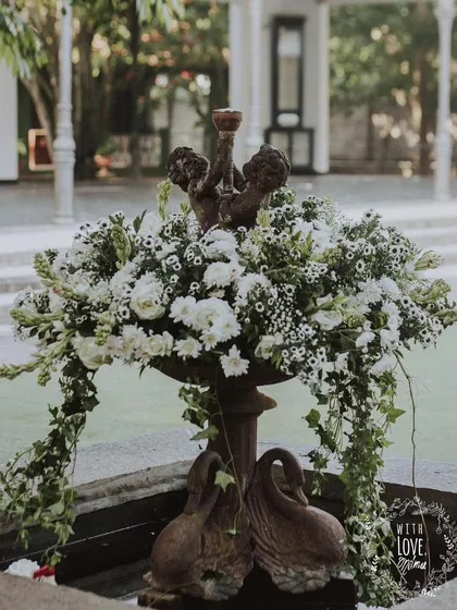 A fountain at the venue becomes a stunning decor piece, filled with an overflowing arrangement of white flowers and cascading ivy.