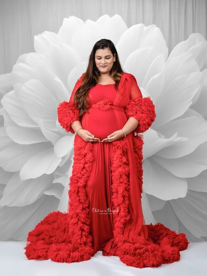 Bold and beautiful. The striking red of the gown against the monochrome floral backdrop creates a high-contrast, artistic maternity portrait.