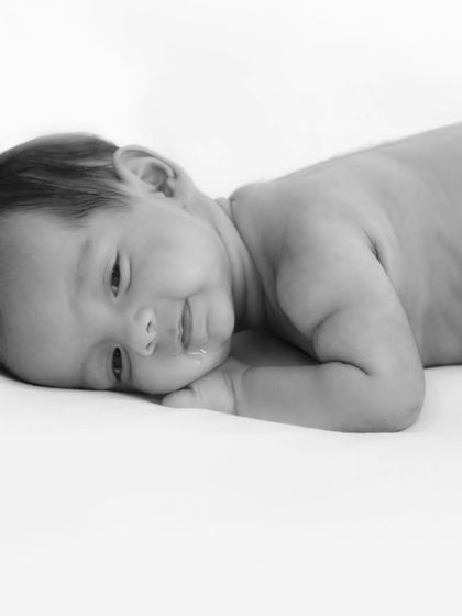 A simple and timeless black and white photo of a baby lying on a clean white background. This minimalist style captures the pure, unadorned innocence of a newborn.