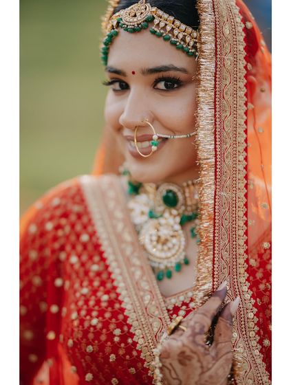 A radiant close-up of bride Rhythm. Her gentle smile and the intricate details of her green jewelry are perfectly captured, showcasing the beauty and grace of a traditional bride.