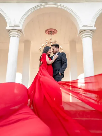 The flowing red trail of the gown perfectly frames the couple under the elegant archway. This is a great example of how to use the gown to create a powerful and romantic composition.