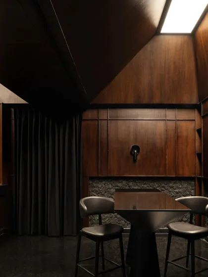 A detail of the private room, where the angular ceiling geometry contrasts with the rich texture of the wood-paneled walls.