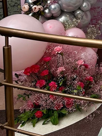 A floor-level view of a floral arrangement paired with pink and silver balloons. This shows how I use decor at multiple levels to create a full, immersive environment for guests.