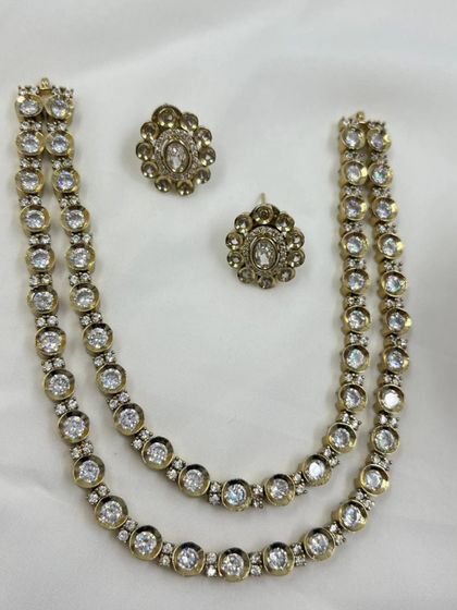 A simple yet elegant two-layer antique gold necklace. This set features evenly spaced Kundan stones and comes with small matching studs, ideal for customers looking for lighter traditional wear.
