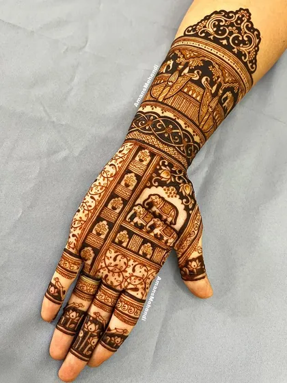 A full view of a hand adorned with a story. The arm features a royal procession, while the palm has panels depicting elephants and other traditional scenes.