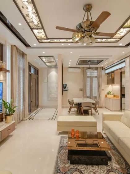 A wider view of the living area, showing the custom ceiling with stained glass panels and the travertine marble TV wall.