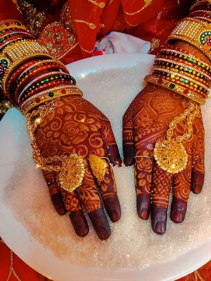 Tasmiya's final bridal look, with her hands adorned with a rich mehndi stain and traditional hathphool jewelry.