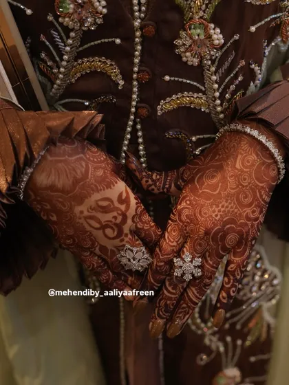 A professional shot capturing the stunning dark stain of a bridal mehendi, complete with personalized initials.