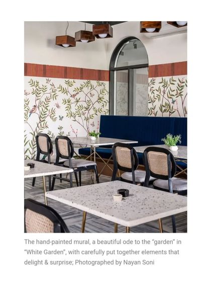 This beautiful hand-painted mural is an ode to a garden, filled with delicate branches and birds. It serves as a stunning backdrop for the dining area, paired with deep blue booth seating and terrazzo-style tables.