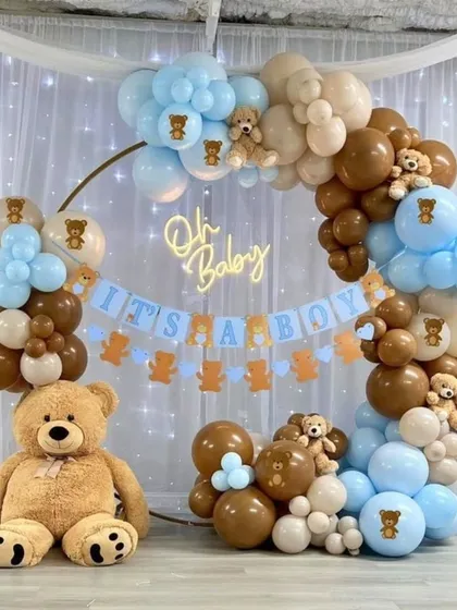 A charming "It's a Boy" baby shower setup with a circular backdrop. This design features a full balloon arch in brown and blue, a large teddy bear, and a custom banner, creating a classic and joyful photo corner.