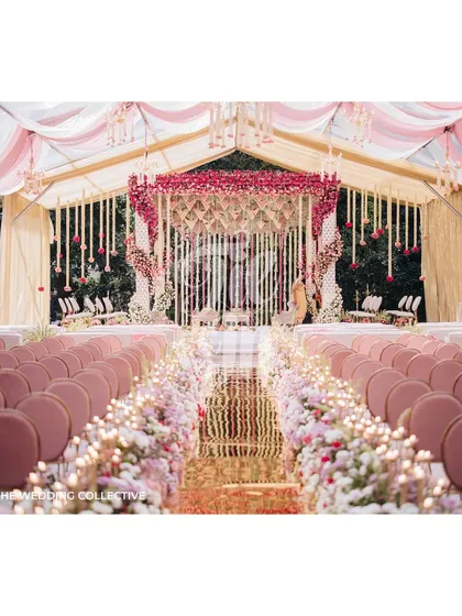 Inspired by the bride's Kanchivaram saree, this Muhurtham ceremony is a testament to our personalized design approach. The aisle is lined with a garden of roses leading to a magnificent floral mandap, all under a canopy of pink and white draped fabric, creating an atmosphere of regal elegance.