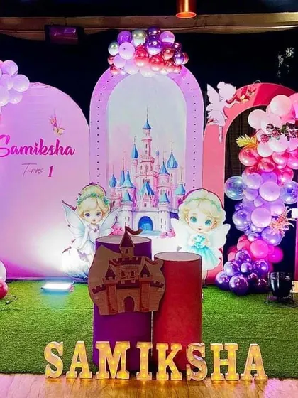 A wider view of the fairy castle birthday theme. This shot shows the full stage with illuminated letters spelling the child's name, multiple character cutouts, and plinths for the cake and other items.