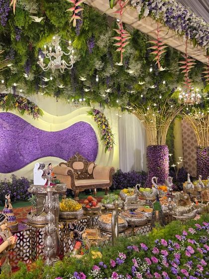 A different perspective of the purple-themed decor, focusing on the interplay of light from the chandeliers with the flowers and greenery.