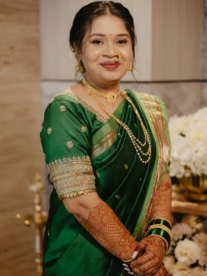 A close-up of a bride in a green saree, showcasing the detailed embroidery on the sleeves and her radiant, natural-looking makeup.