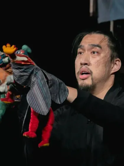 A puppeteer from Taiwan skillfully operates two traditional glove puppets at once in 'Hiss & Arf'. This wordless performance humorously portrays the classic battle between a cat and a dog.