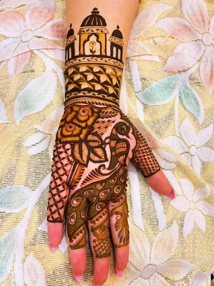 This unique design combines a majestic peacock on the palm with an architectural dome, reminiscent of a temple or palace, on the wrist. It's a beautiful blend of nature and traditional Indian architecture.