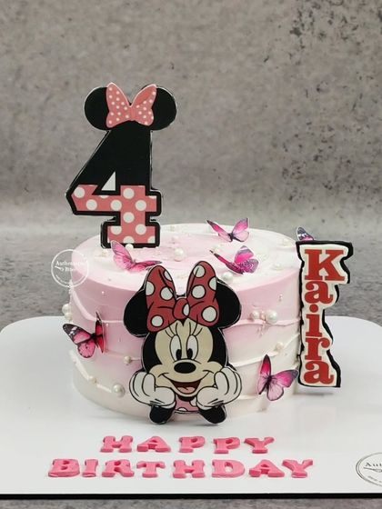A sweet Minnie Mouse cake for a 4th birthday. This pink cake is decorated with Minnie, butterflies, and a custom name and age topper.