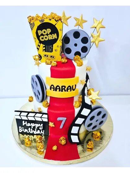 Lights, camera, action! This movie-themed cake is perfect for a young film buff, decorated with a red carpet, film reels, a popcorn box, and a clapperboard. It’s a fun and unique design for a seventh birthday.