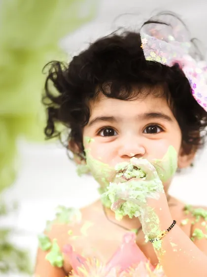A close up portrait of the birthday girl getting a good taste of her cake. These messy faces make for the most adorable first birthday photos.