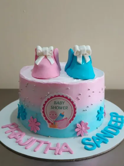 A baby shower cake for twins, featuring adorable pink and blue fondant baby booties.