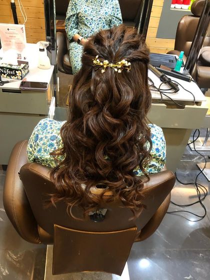 A romantic half-up, half-down hairstyle with voluminous curls and a delicate hair accessory. This is a popular choice for weddings and formal events.