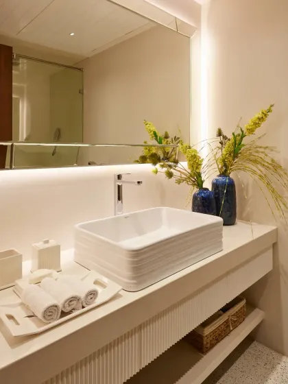 An all-white bathroom can feel incredibly serene and spa-like. Here, a textured vanity, a clean rectangular sink, and soft, backlit mirror lighting create a space that is both calming and bright.
