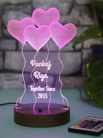 Celebrate your journey together with this custom lamp. It features your names and the year you got together, engraved below a design of heart-shaped balloons, and comes with a remote to change the light color.