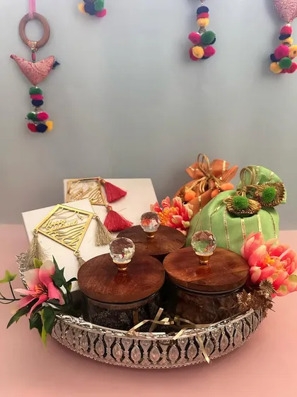 A beautiful Sankranti hamper set in an ornate silver crystal basket. It includes jars of treats, gift boxes, and a festive potli, blending tradition with luxurious presentation.