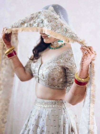 A beautiful portrait of a bride, her face partially covered by her sheer, embellished veil.